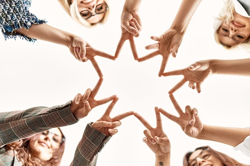 Group of young businesswoman smiling happy making victory symbol with hands and fingers together at the office.