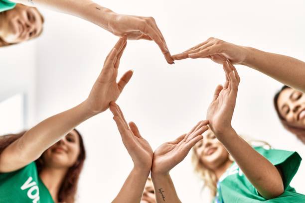 행복한 미소를 지은 젊은 자원 봉사자 그룹 그룹은 자선 센터에서 함께 손으로 심장 상징을 만듭니다. - 원조 뉴스 사진 이미지