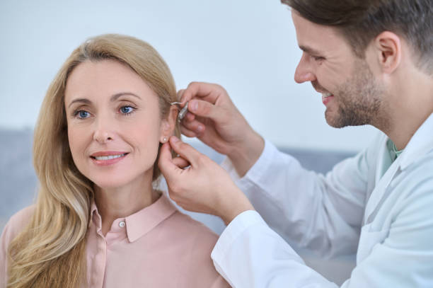istock Joyous pleasant doctor fixing a deaf aid behind the womans ear 1333968731