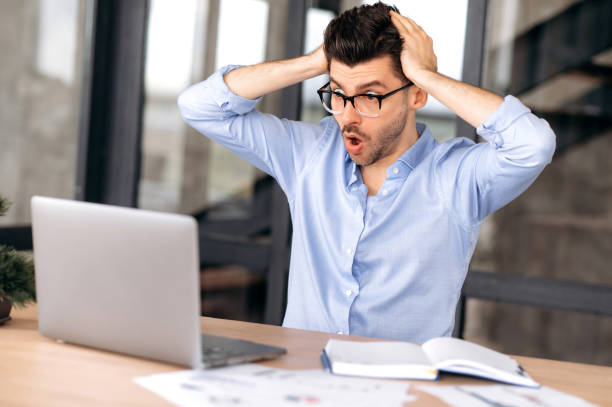 istock Shocked caucasian male manager, broker or freelancer, working in office, using laptop, incurring huge losses, overworked, stressed, looking at screen in surprise, holding his head with his hands 1333969071