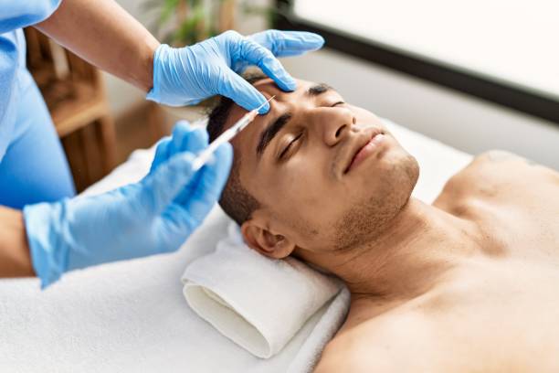 Doctor injecting botox on man face for anti aging treatment at the clinic. stock photo