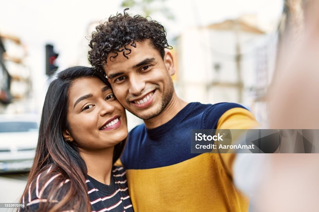 Young latin couple smiling happy and hugging make selfie by the camera at the city. Couple - Relationship Stock Photo