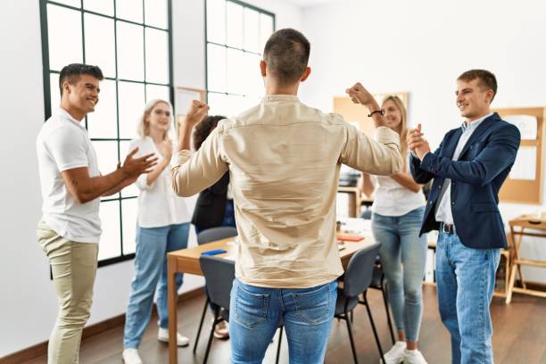 istock Group of young business workers smiling and clapping. Young businessman doing strong gesture with arms on back view at the office. 1333970476