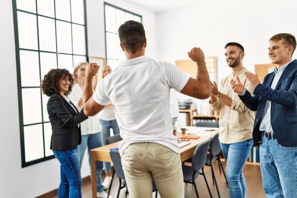 istock Group of young business workers smiling and clapping. Young businessman doing strong gesture with arms on back view at the office. 1333970481