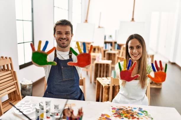 istock Two hispanic students smiling happy showing colorulf painted hands at art studio. 1333970818