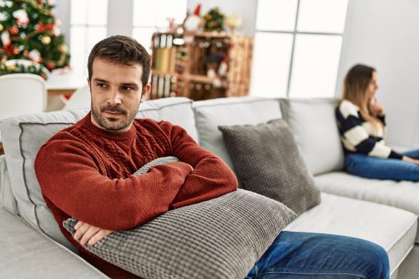 giovane coppia ispanica con problemi seduti sul divano in silenzio a casa. - holiday emotional stress christmas santa claus foto e immagini stock