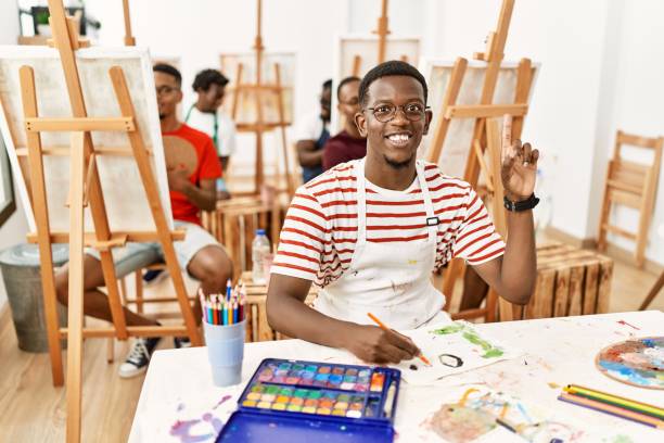 istock Young african man at art studio surprised with an idea or question pointing finger with happy face, number one 1333972568