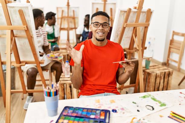 istock Young african man at art studio celebrating victory with happy smile and winner expression with raised hands 1333972575