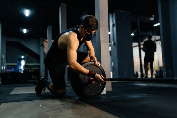 istock Athlete wearing a mask and disinfecting weights 1333972924