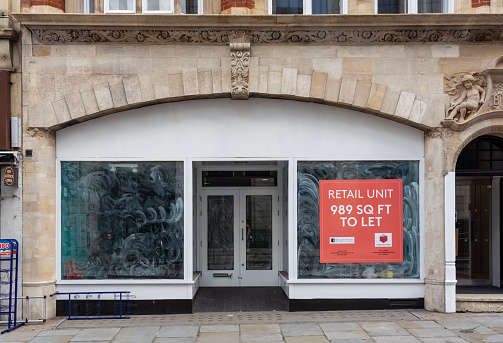 London, UK - An empty retail unit on a street in central London, with a real estate advertisement in the window.