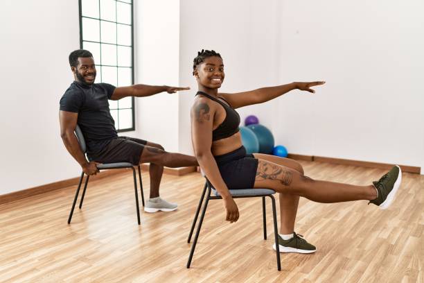 młoda afroamerykańska para uśmiecha się szczęśliwy trening na krześle w centrum sportowym. - sitting pose zdjęcia i obrazy z banku zdjęć