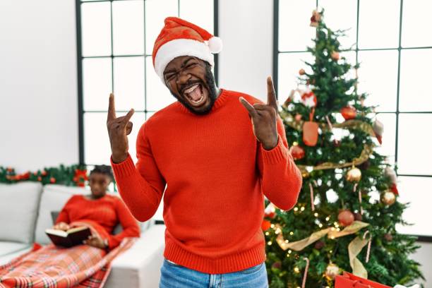 istock Young african american man standing by christmas tree shouting with crazy expression doing rock symbol with hands up. music star. heavy concept. 1333975405