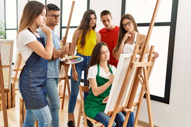 istock Group of people with serious expression looking draw of partner at art studio. 1333975698