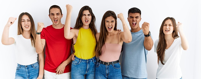 Group of people wearing casual clothes standing over isolated background angry and mad raising fist frustrated and furious while shouting with anger. rage and aggressive concept.