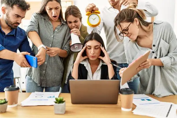 Photo of Group of business workers screaming to stressed partner at the office.