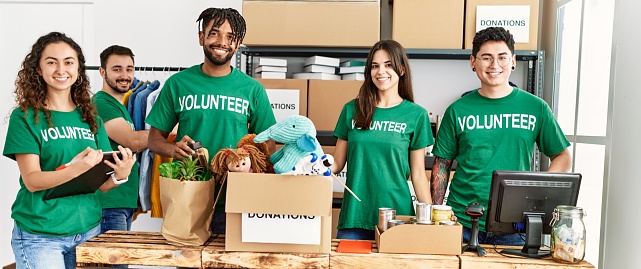 Group of young volunteers smiling happy working at charity center.