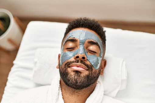 Man relaxed with facial treatment at beauty center.