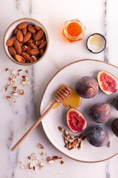 istock Raw figs with honey and almonds on a marble surface and rustic plate with wooden honey drizzler 1333978112