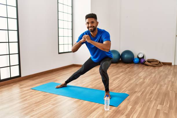 istock Handsome hispanic man doing exercise and stretching on yoga mat, practicing flexibility and training at the gym 1333978118