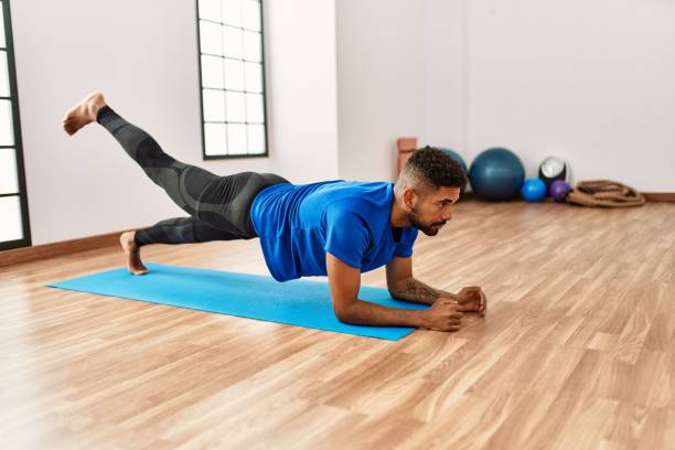 istock Handsome hispanic man doing exercise and stretching on yoga mat, practicing flexibility and training at the gym 1333978125