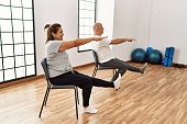 istock Middle age hispanic couple stretching using chair at sport center. 1333981795