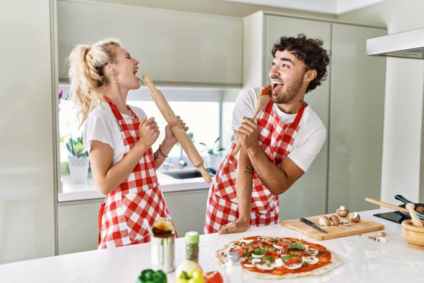 istock Young couple smiling happy and singing using kneader and spoon as a microphone at kitchen. 1333982031