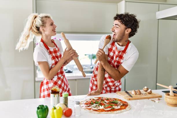 istock Young couple smiling happy and singing using kneader and spoon as a microphone at kitchen. 1333982032