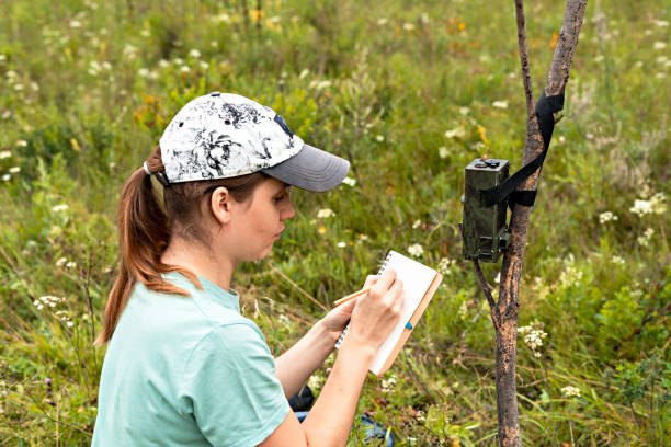 istock Young woman scientist zoologist writing down data from trap camera to notepad, observing wild animals in taiga forest, monitoring of rare and endangered animal species, ecology World Wildlife Day 1333982329