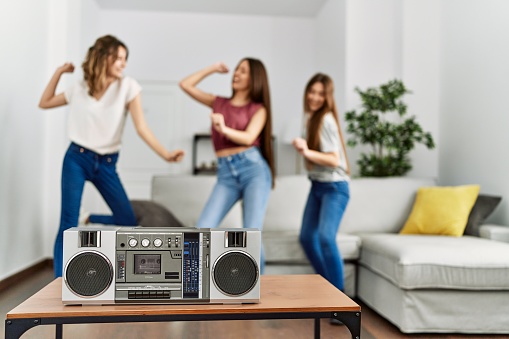 Three young hispanic woman smiling happy and dancing at home.