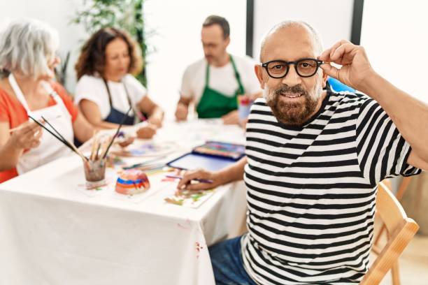 istock Group of middle age draw students sitting on the table drawing at art studio. Man smiling happy looking to the camera. 1333983331