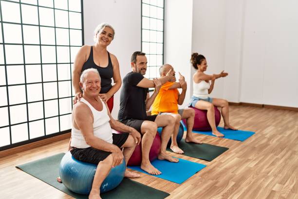 istock Group of middle age people training using fit ball with personal trainer at sport center. 1333983388