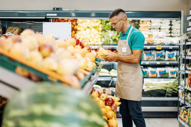 istock Employee in supermarket arranging fresh fruit 1333984216