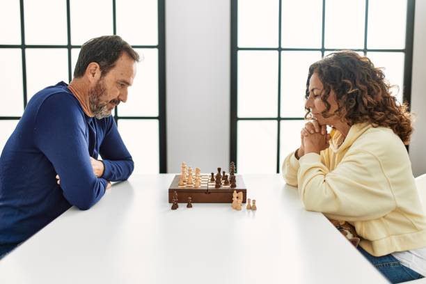 istock Middle age hispanic couple concentrated sitting on the table playing chess at home. 1333984360