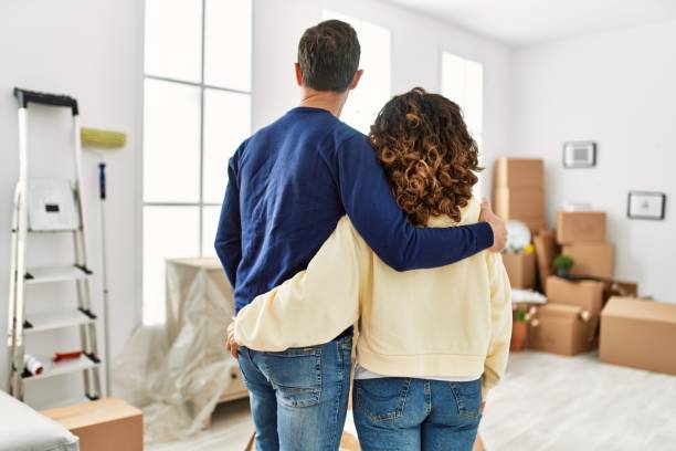 istock Middle age hispanic couple on back view hugging and standing at new home. 1333984400