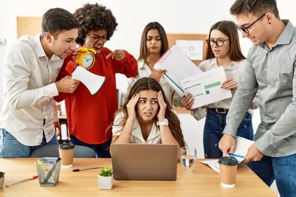 Photo of Group of business workers screaming to stressed partner at the office.