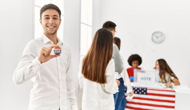 group of young american voter people putting vote in ballot. man smiling happy and holding i voted badge at electoral center. - jovens a votar imagens e fotografias de stock