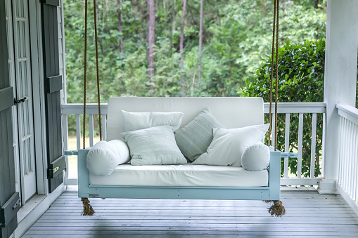 A luxurious and classic outdoor bed swing painted a seafoam green with white deep cushions