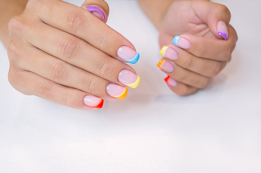 Manos de una mujer joven con una manicura. Las uñas están cubiertas con esmalte de gel con color francés. photo