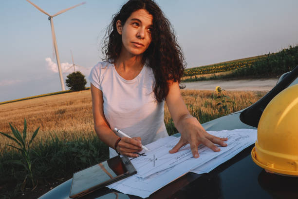 Wind turbines inspection field work Female scientist working in the field, inspecting wind turbine efficiency. She is checking blueprints and real time inspection via digital tablet. stem research stock pictures, royalty-free photos & images
