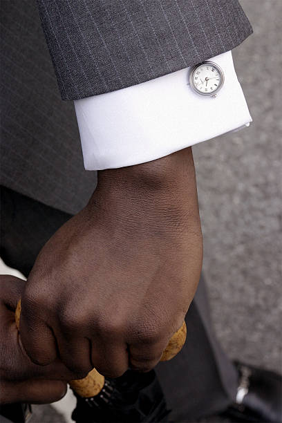 A man wears speciality cufflinks and holds a luxury umbrella.