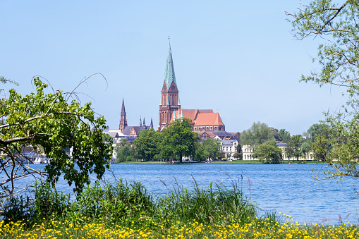 Schwerin cathedral St. Marien and St. Johannis, one of the earliest large examples of brick gothic architecture, seen from the lake shore in the state capital city of Mecklenburg Vorpommern, Germany, blue sky with copy space