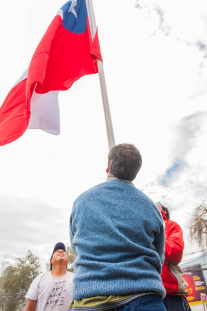 Santiago de Chile, Chile - September 1, 2019: A group of workers hoisting Chilean flag at the street in a cloudy winter day, some days before Chilean National Day, September 18th.