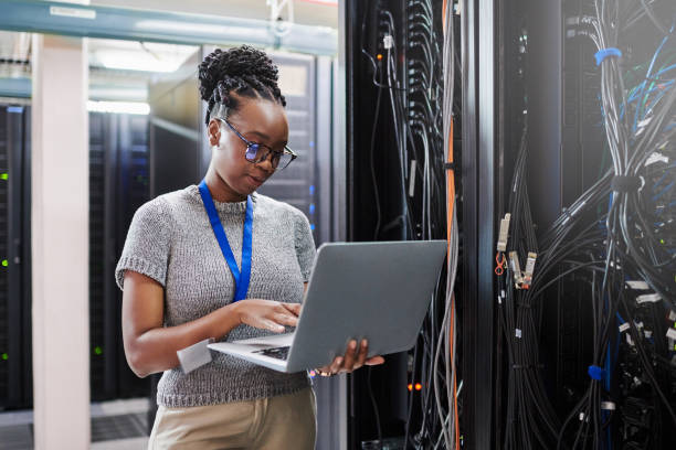 サーバールームでラップトップを使用している若い女性のショット - telecommunications equipment technician repairing engineer ストックフォトと画像