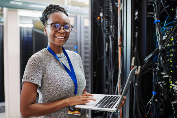 サーバールームでラップトップを使用している若い女性の肖像画 - telecommunications equipment technician repairing engineer ストックフォトと画像