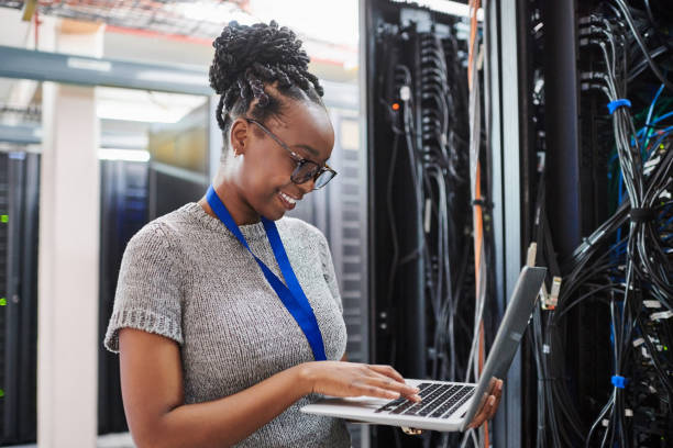 istock Shot of a young woman using a laptop in a server room 1334004071