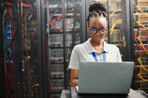 istock Shot of a young woman using a laptop in a server room 1334004103