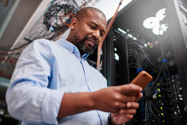 istock Shot of a mature man using a cellphone in a server room 1334004258