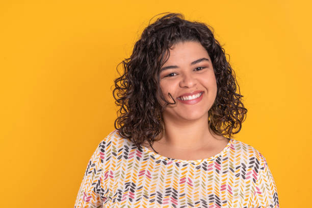 porträt junge frau lächelt auf gelbem hintergrund - brasilianischer abstammung stock-fotos und bilder