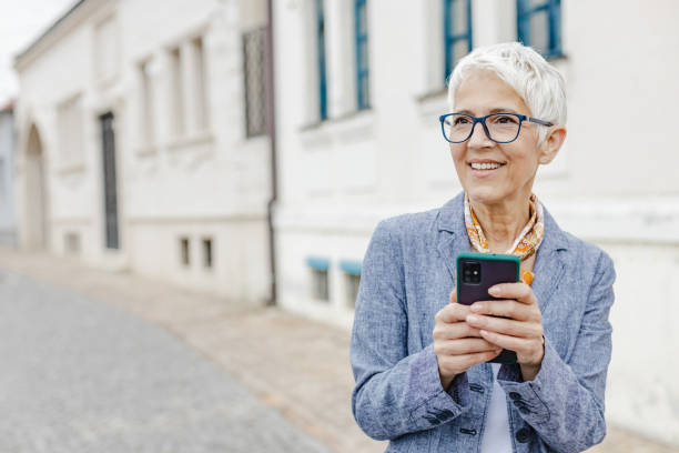 istock Senior woman is using mobile phone on the street 1334006778