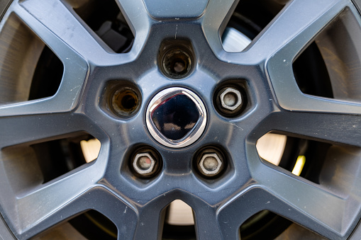 A close up view of the rim and wheel of a car with two broken lug nuts